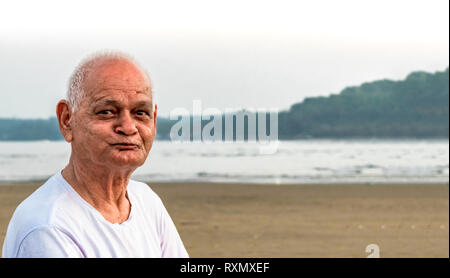 Super Senior Citizen nella sua metà anni ottanta, ponendo alla telecamera felicemente, pur rendendo volti felici e vivendo la sua vita in pensione allegramente su una spiaggia Foto Stock