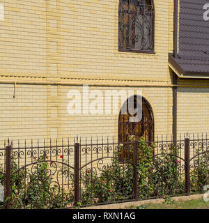 Casa del mattone giallo e marrone e tetto ondulato in metallo. Tralicci su windows Foto Stock