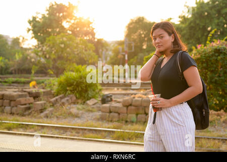 Giovani asiatici donna turistico backpacker soda tenuta presso la stazione ferroviaria Foto Stock