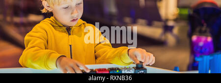 Il bambino gioca con il progettista elettronico sul tavolo luminoso. BANNER, formato lungo Foto Stock