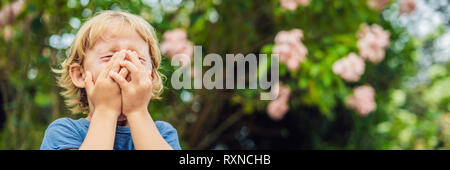 Ragazzo soffia il naso di fronte ad albero in fiore. Molla il concetto di allergia. I bambini di allergie. BANNER, formato lungo Foto Stock