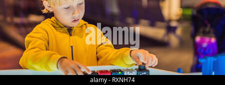 Il bambino gioca con il progettista elettronico sul tavolo luminoso. BANNER, formato lungo Foto Stock