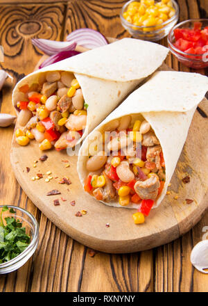 Burrito in tartilla con carne e verdure, fagioli bianchi, il peperone rosso, il mais. Delizioso pranzo, cibo messicano, spuntini fatti in casa Foto Stock