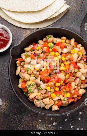 La cottura di riempimento per burrito in tortillas con carne e verdure, fagioli bianchi, il peperone rosso, il mais. Delizioso pranzo, cibo messicano, spuntini fatti in casa Foto Stock