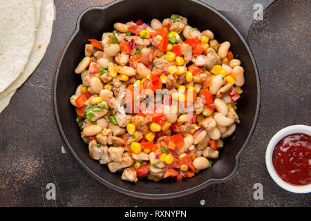 La cottura di riempimento per burrito in tortillas con carne e verdure, fagioli bianchi, il peperone rosso, il mais. Delizioso pranzo, cibo messicano, spuntini fatti in casa Foto Stock