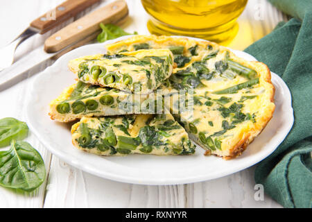 Frittata con spinaci e fagiolini, cibo sano. L'uovo e il latte Frittata, deliziosa colazione in bianco sullo sfondo di legno Foto Stock