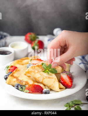 Thin pancake con fragole e mirtilli, marmellate, latte condensato, deliziosa prima colazione. Il russo dolce tradizionale per la celebrazione Shrovetide (mas Foto Stock