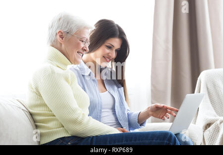 Insegnamento figlia sua anziana madre utilizzando laptop Foto Stock