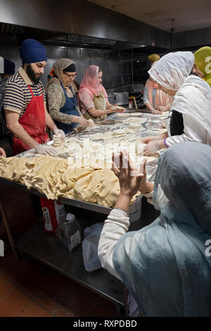 Donne e uomini volontari per un langar, un tempio sikh cucina, preparare roti, una rotonda pane sottile. In South Richmond Hill, Queens, a New York City. Foto Stock