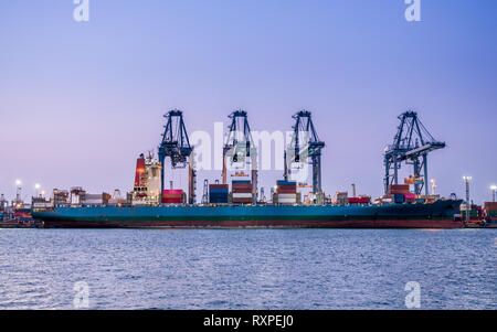 Il caricamento di container nave porto al crepuscolo in Sriracha porto industriale, Chonburi, Thailandia. Foto Stock