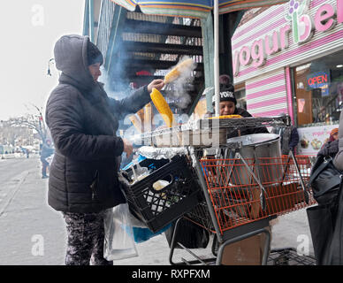 In una fredda giornata invernale, due donne vendere fresco di mais alla griglia. Su 82st in Jackson Heights, Queens, a New York sotto il #7 treno scalinata. Foto Stock