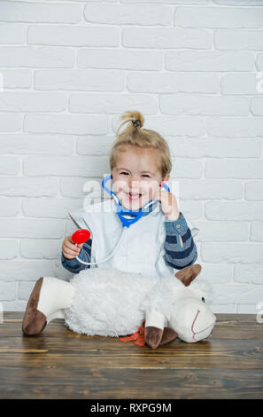 Happy Child play medico con toy pecore sul muro bianco Foto Stock