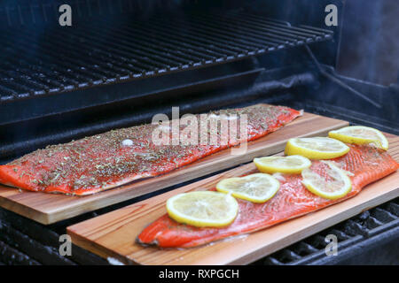 Un filetto di salmone alla griglia direttamente sul barbecue utilizzando un legno di cedro infonderà un meraviglioso sapore di fumo Foto Stock