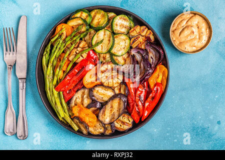 Verdure alla griglia su una piastra con salsa, vista dall'alto. Foto Stock