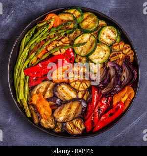 Verdure alla griglia su una piastra con salsa, vista dall'alto. Foto Stock