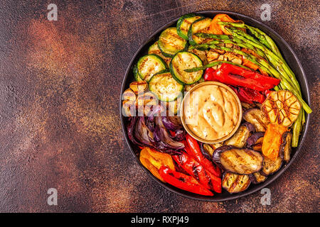 Verdure alla griglia su una piastra con salsa, vista dall'alto. Foto Stock