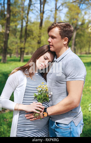 Godendo della gravidanza insieme.la famiglia insieme in estate park. La donna è in stato di gravidanza Foto Stock