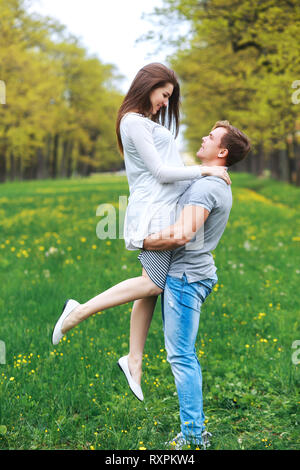 Uomo che porta la sua donna incinta nel parco.ritratto della bella futuri genitori nella giornata di sole nel parco Foto Stock