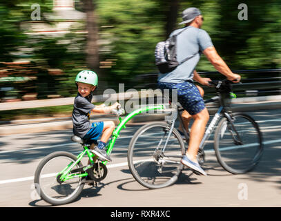 La città di New York, Stati Uniti d'America - 15 August 2018: Padre e figlio in sella a una moto con un attacco sul retro a central park con uno sfondo sfocato. Foto Stock