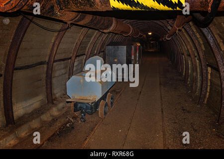 Vecchio Gabinetto di carro e miniera di metallo in treno in galleria di miniera con timbering in legno Foto Stock