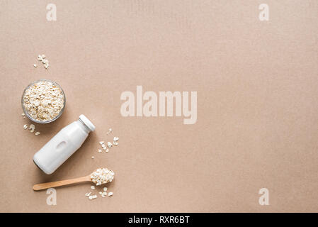 Latte di avena alternativa su sfondo beige, copia spazio, vista dall'alto. Vegano sano sostituto dairy drink gratuito - bottiglia di latte di avena. Foto Stock