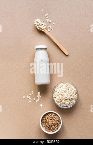 Latte di avena alternativa su sfondo beige, copia spazio, vista dall'alto. Vegano sano sostituto dairy drink gratuito - bottiglia di latte di avena. Foto Stock