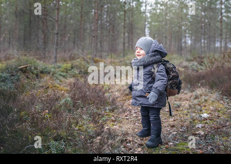 Little Boy fare escursioni con zaino sulla foresta in un freddo giorno Foto Stock