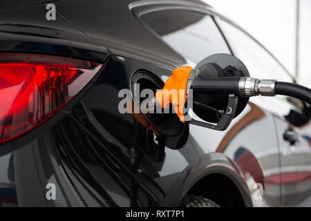 Nero nuova vettura refuels presso la stazione di gas. Pistola in gas-serbatoio. Foto Stock