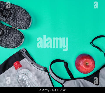 Tessuto nero scarpe e altri elementi per il fitness su uno sfondo verde, vista dall'alto Foto Stock