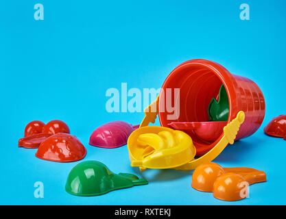 Baby rosso in plastica cucchiaio e altri elementi per giocare su uno sfondo blu Foto Stock