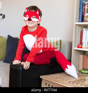 Bambino in fox fancy dress maschera seduti sul divano imitando un vero fox Foto Stock