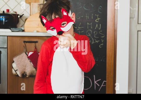 Bambino in fox fancy dress maschera, stoviglie e lavagna con alfabeto in background Foto Stock