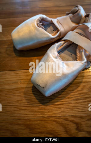 Ritagliate nella immagine di una coppia di balletto classico pointe shoes, ballerine e Pointe scarpe su un pavimento di legno Foto Stock