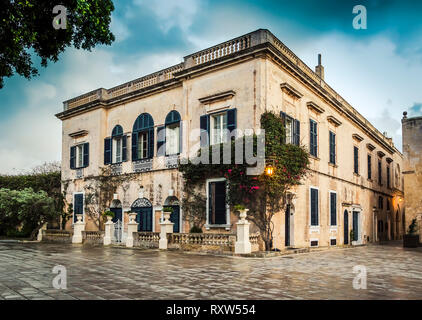 Mdina, Malta: medievale townhouse a Bastion Square con finestre artistiche, pianta rampicante e lanterna luce. Aspetto cupo Foto Stock