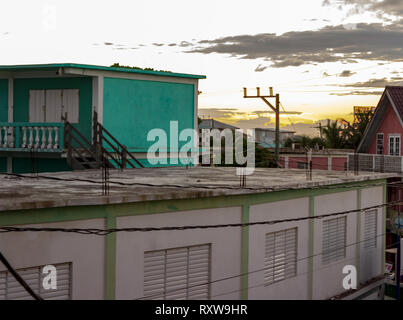 Uno scorcio del tramonto può essere visto attraverso i tetti di San Pedro, Ambergris Caye Belize. Foto Stock