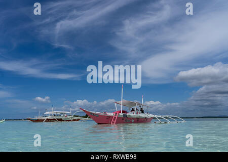 Un tradizionale outrigger barca ormeggiata in un'area poco profonda di acqua a sandbar,Bohol,Filippine Foto Stock