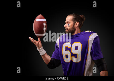 Giocatore di football americano gettando la sfera su sfondo nero Foto Stock