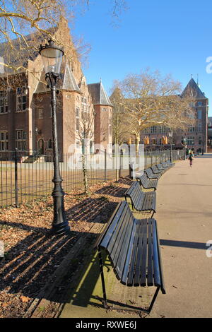 Una fila di panche di Oosterpark, con la facciata esterna del Tropenmuseum sulla sinistra, Amsterdam, Paesi Bassi Foto Stock