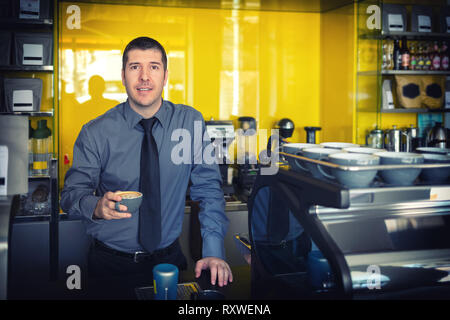 Ritratto di proprietario di piccola impresa sorridente e in piedi dietro il contatore interno coffee shop Foto Stock