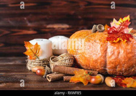 Concetto di autunno. Zucca, ghiande, foglie di giallo, cannella su sfondo scuro Foto Stock