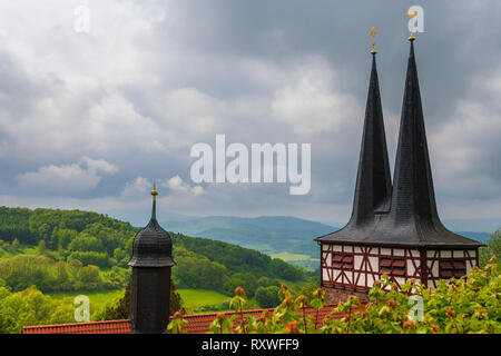 Ottima vista dal castello di Hanstein sopra il tetto della chiesa cattolica in Rimbach con le sue due torri e il bellissimo paesaggio di Hesse con il... Foto Stock