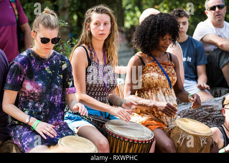 I frequentatori del festival frequentare un outdoor drumming workshop nei boschi a nel selvaggio festival, Kent, Regno Unito Foto Stock