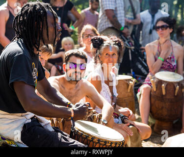 I frequentatori del festival frequentare un outdoor drumming workshop nei boschi a nel selvaggio festival, Kent, Regno Unito Foto Stock