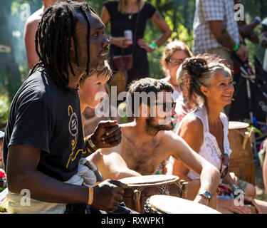 I frequentatori del festival frequentare un outdoor drumming workshop nei boschi a nel selvaggio festival, Kent, Regno Unito Foto Stock