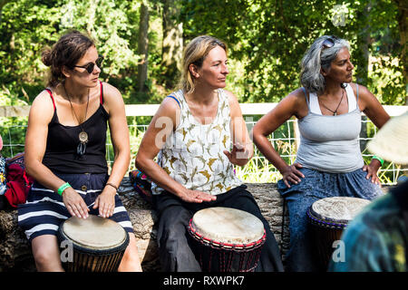 I frequentatori del festival frequentare un outdoor drumming workshop nei boschi a nel selvaggio festival, Kent, Regno Unito Foto Stock