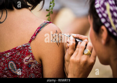 Ragazza pittura henna tattoo sulla spalla a nel selvaggio festival, Kent, Regno Unito Foto Stock