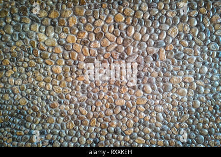 Una parete in muratura fatta di ciottoli e pietre rotonde Foto Stock