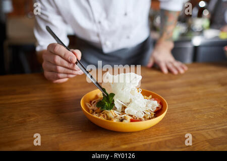 Lo chef serve piatti asiatici Foto Stock