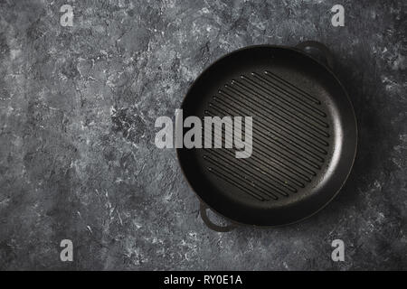 Svuotare round vecchia padella per grigliare su pietra scura sullo sfondo vista superiore Foto Stock