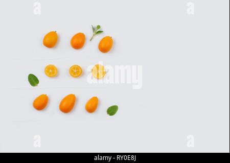 Kumquat. Fresche raccolte organiche di agrumi kumquat interi e tagliati in pezzi . Sfondo senza giunture con frutti e foglie. Immagine con spazio copia,orientat orizzontale Foto Stock